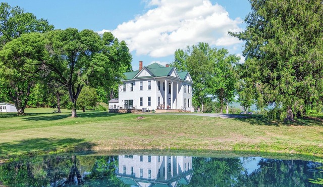 Historic countryside farmhouse with cozy interiors, scenic views, porch, game room, and trails.