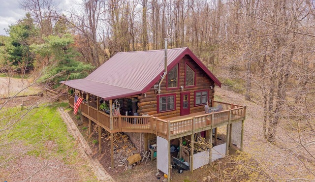 Peaceful log cabin retreat with wraparound deck, open living space, full kitchen, cozy bedrooms & scenic wooded views.
